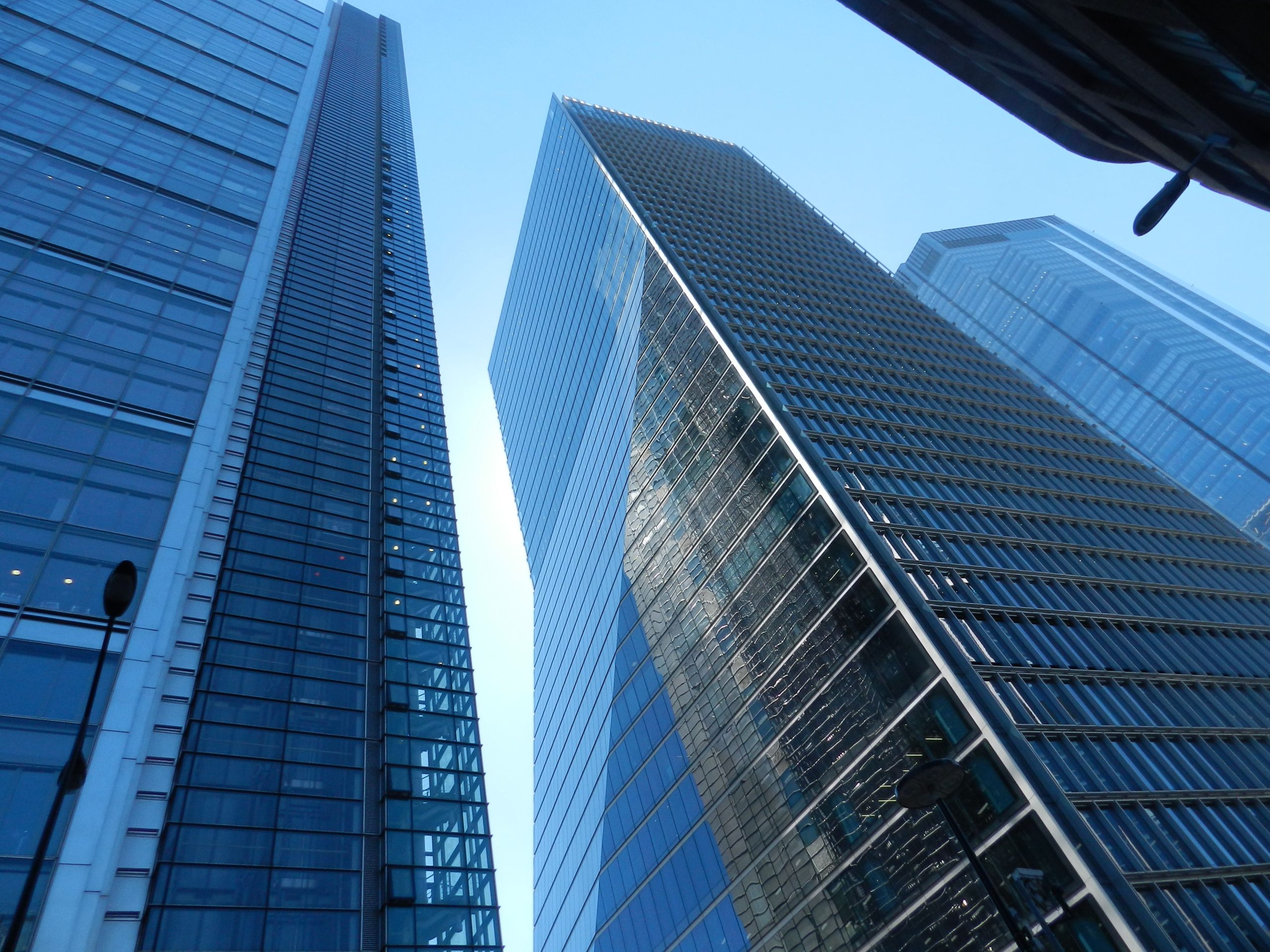 Upward view of modern skyscrapers with reflective glass in a vibrant cityscape.